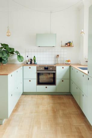 Scandinavische mintgroene keuken met houten werkbladen en houten vloeren