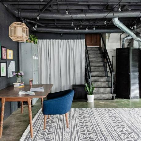 Escritório na garagem preta com tapete estampado e mesa com cadeira azul