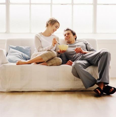 Vista de ángulo bajo de una pareja sentada en un sofá y comiendo