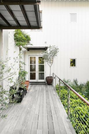 exterior de casa branca com deck cinza e trilhos modernos