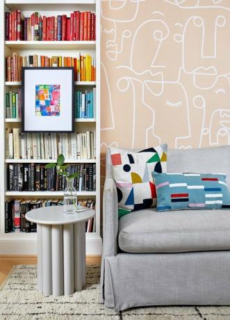 Papéis de parede e livros codificados por cores em uma biblioteca de home office por Zoe Feldman