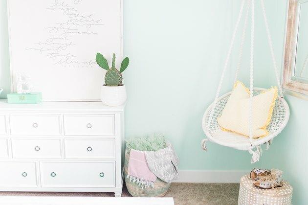 aqua kleur slaapkamer met wit dressoir en witte hangstoel