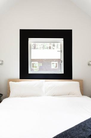 Um quarto branco minimalista com uma janela em moldura preta