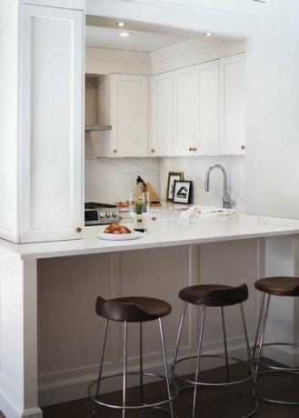bijela apartmanska kuhinja s mesinganim okovom