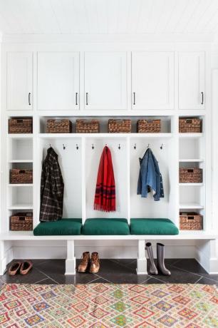 depósito de mudroom com armários brancos, piso de ardósia e tapete eclético