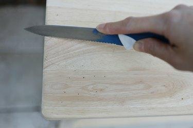 Affettare e graffiare la superficie del legno con un coltello seghettato