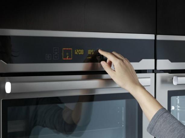 Donna che utilizza forno nella cucina domestica