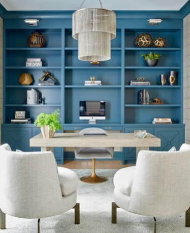 Blauw ingebouwde boekenplanken, bureau, stoel, accentstoelen, kroonluchter.