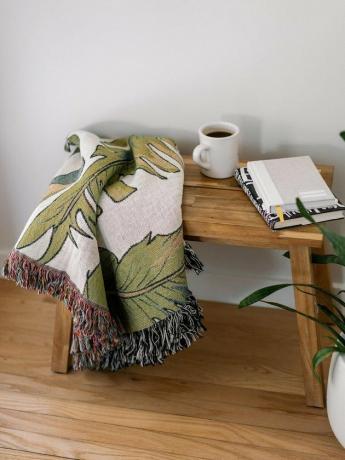 mesa de madeira com manta estampada de folha de palmeira