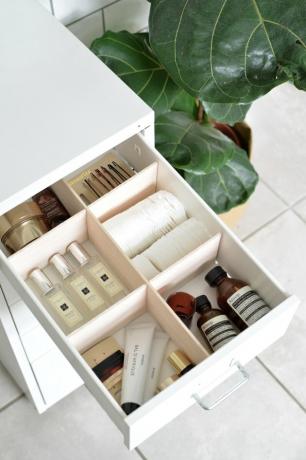 Ideias para organizadores de maquiagem em uma gaveta aberta do banheiro com divisórias e cosméticos