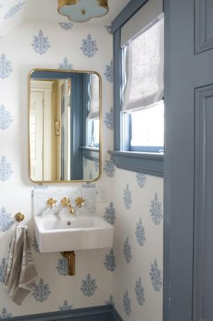 blauw-witte badkamer onder trap met hangende wastafel en messing armaturen