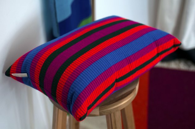 Almohada de rayas de colores en taburete de madera