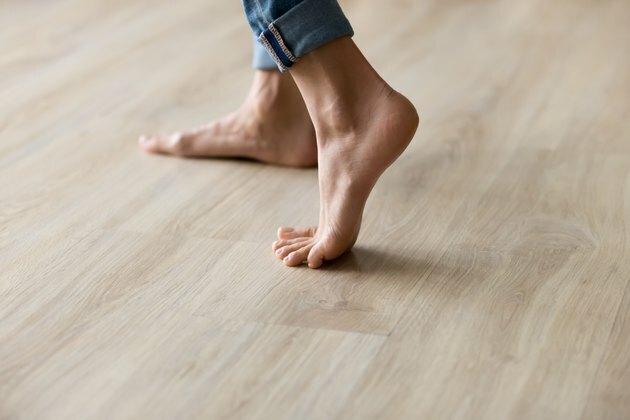 I piedi laterali della donna di vista del primo piano stanno sul pavimento di legno caldo