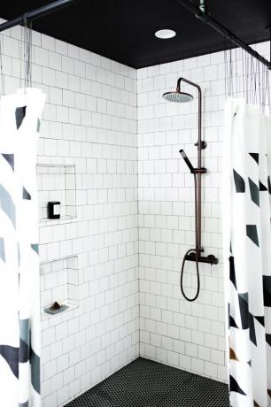 Chuveiro de canto com paredes de azulejos brancos e cortinas de chuveiro preto e branco