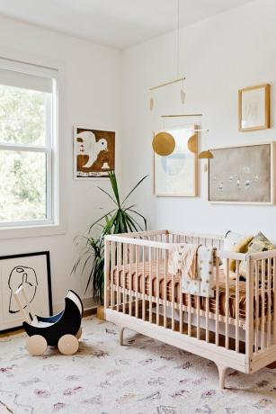 witte minimalistische kinderkamer inrichting met houten wieg en tapijt