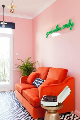 roze kamer woonkamer met rode bank en groen neonlicht