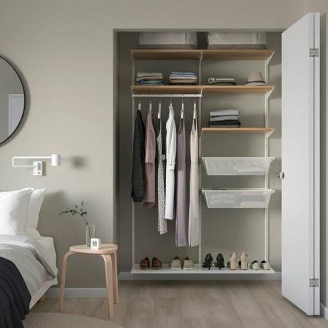 Quarto com unidade organizadora de armário, roupas, sapatos, mesa de cabeceira.