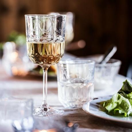 copo de vinho na mesa com salada por perto