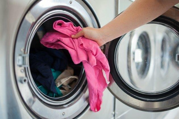 Mujer poniendo camisa en lavadora