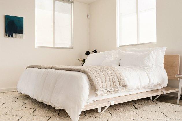 Houten bedframe met witte sprei in de moderne slaapkamer van Californië