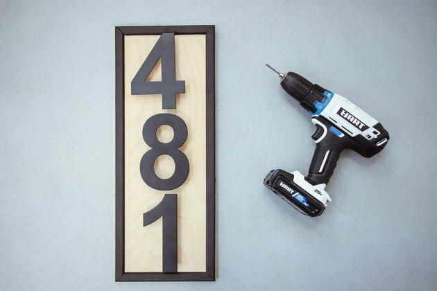Números de casas pretos modernos presos a uma placa de madeira com furadeira