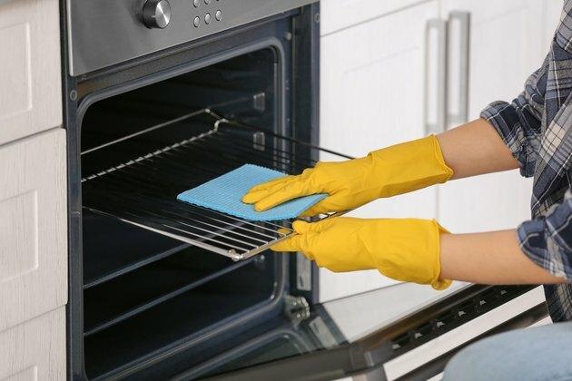 Vrouwen schoonmakende oven in keuken, close-up