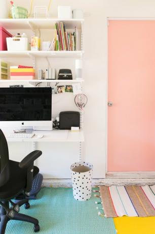 Escritório na garagem com porta rosa e computador na mesa