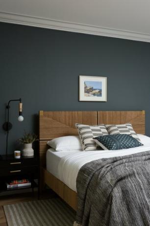 cameră de oaspeți cu perete albastru închis și cadru de pat din lemn