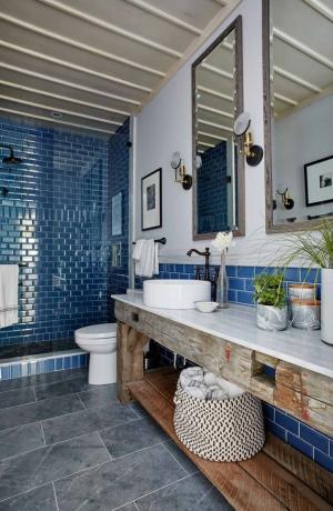 Azulejo azul do chuveiro em um tom marinho no banheiro da casa de fazenda