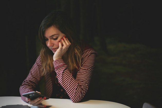 vrouw zitten aan tafel met smartphone