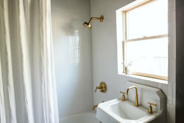 industriell våningshus hvit vask med en gullkran og hvite fliser på et bad