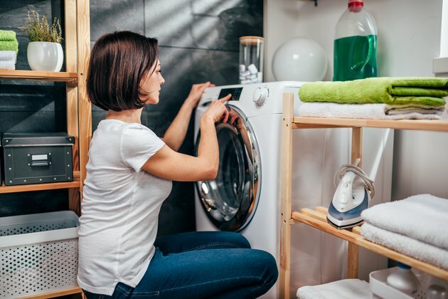 Женщина выбирает программу на стиральной машине