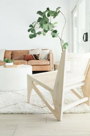 Bijela boho dnevna soba s kožnim kaučem i smokvinim lišćem