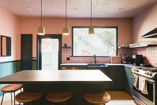 roze en groene keuken met grote eettafel en roze tegeltableau