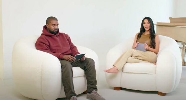 Kanye West et Kim Kardashian-West assis sur des chaises blanches avec piano en arrière-plan