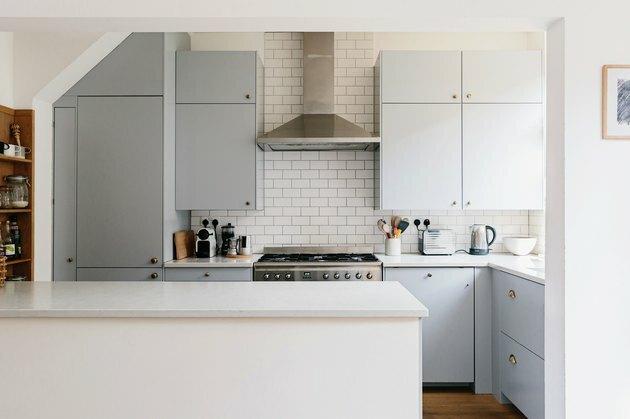 Backsplash de telha de metrô na cozinha com armários azuis claros.