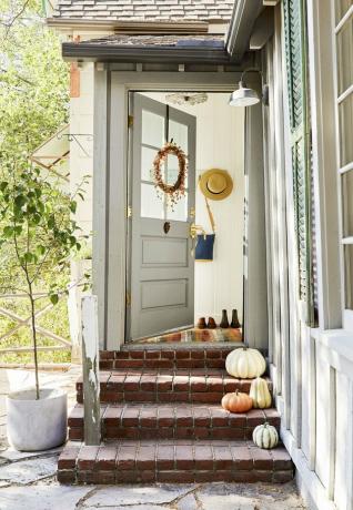 decoração de varanda de outono com coroa na porta e abóboras nos degraus