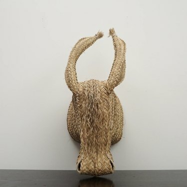 Escultura tejida a mano de un burro de paja en una pared blanca