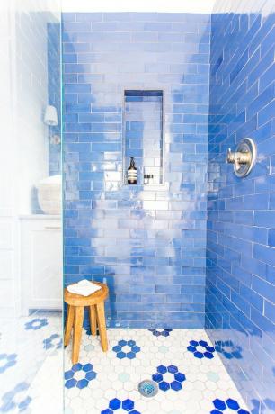 Chuveiro costeiro com paredes de ladrilhos azuis e piso floral branco e azul