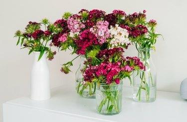 Lyserøde og hvide blomsterarrangementer i glasvaser