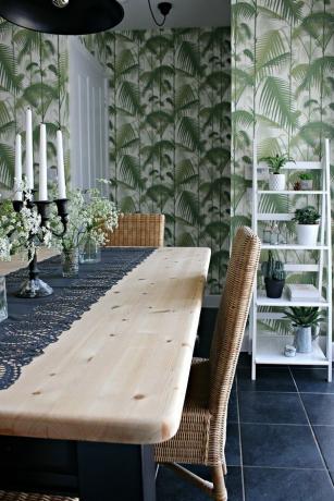 Groene boho kamer met natuurlijke houten tafel en palmblad behang